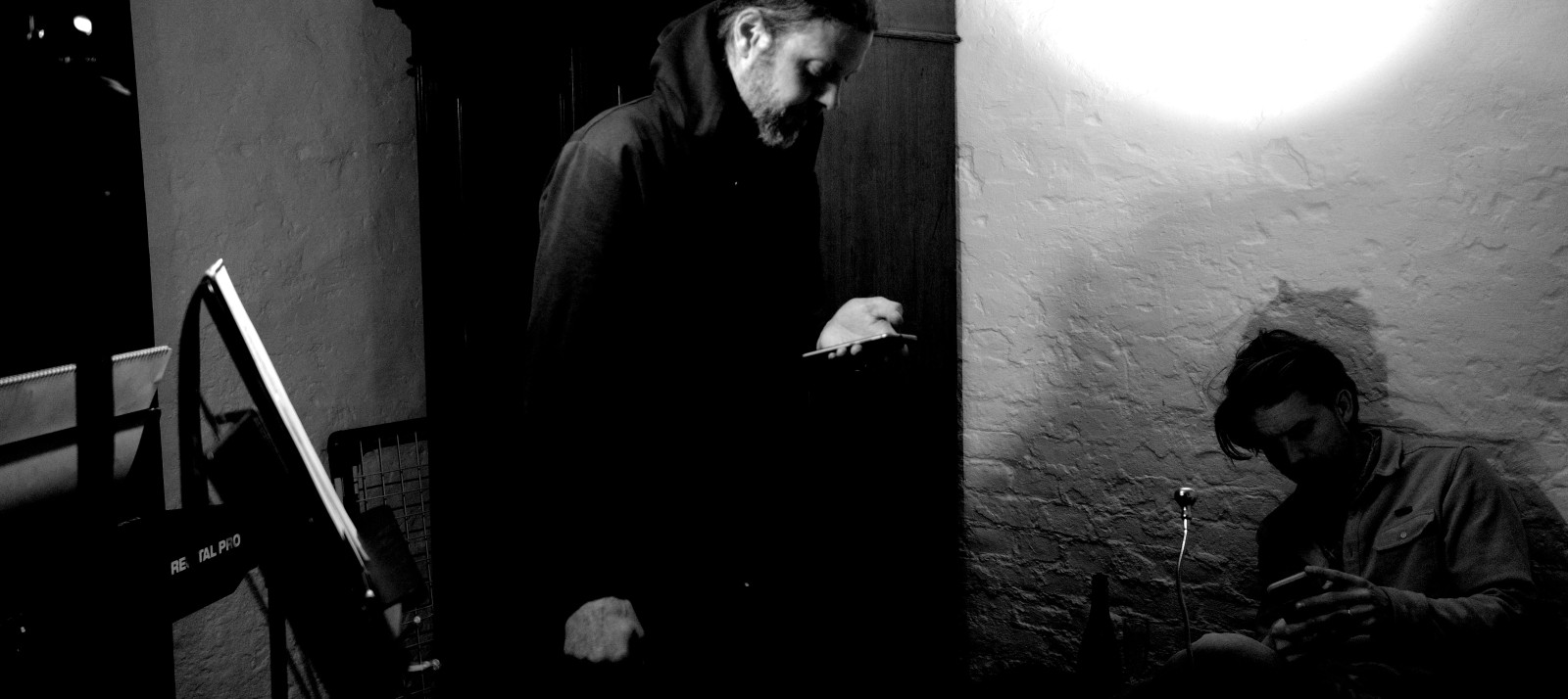 Scene from the rehearsal room, Till and Leon on their phones.